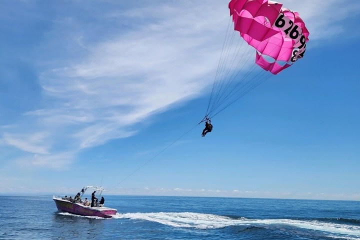 a person flying a kite in a boat on a body of water